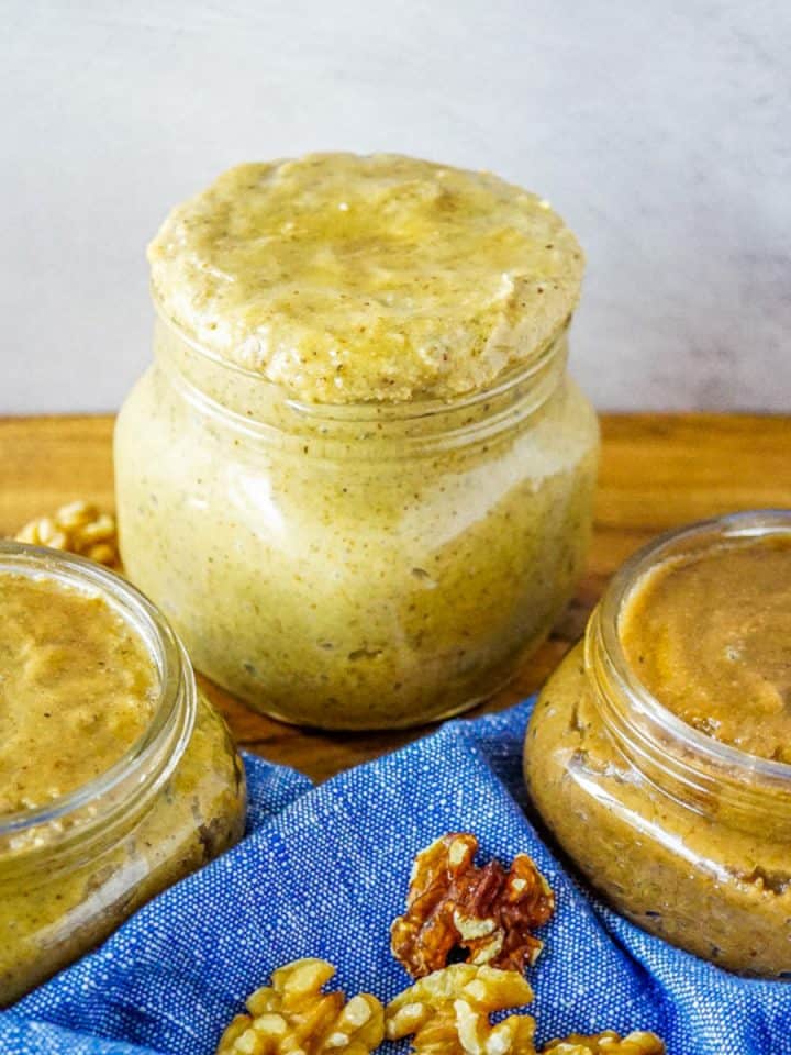 Three jars of different types of walnut butter: honey cinnamon, regular, and cacao.